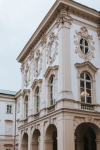 Ein historisches Gebäude mit kunstvollen architektonischen Details, Bogenfenstern und dekorativen Reliefs an der Fassade – eine perfekte Kulisse für eine romantische Hochzeit. Seine sanfte Elfenbeinfarbe bildet einen schönen Kontrast zum bewölkten Himmel und macht es zu einem idealen Ort für eine unvergessliche Hochzeitsplanung.