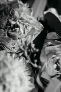 Schwarz-weiße Nahaufnahme eines gemischten Blumenstraußes mit Rosen und Chrysanthemen, wie man ihn oft bei Hochzeitsplanungen sieht. Der weiche Fokus erzeugt ein strukturiertes, abstraktes Erscheinungsbild, perfekt, um die Essenz von Heiraten einzufangen.