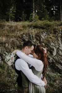 Ein Paar umarmt sich liebevoll vor einer Felswand und feiert in intimer Wärme seine Hochzeit.