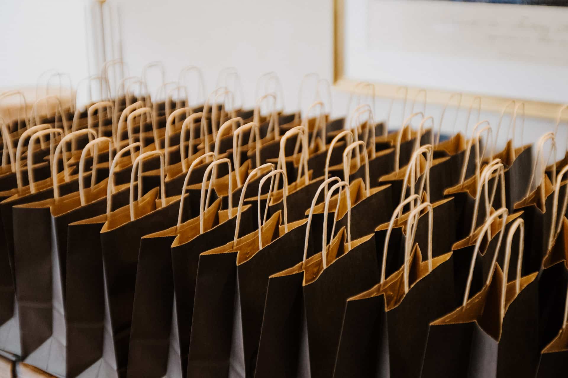 Eine große Gruppe brauner Papiertüten mit Henkeln, die ordentlich auf einem Tisch aufgereiht sind, bereit für die Verteilung bei Lebensfeiern.