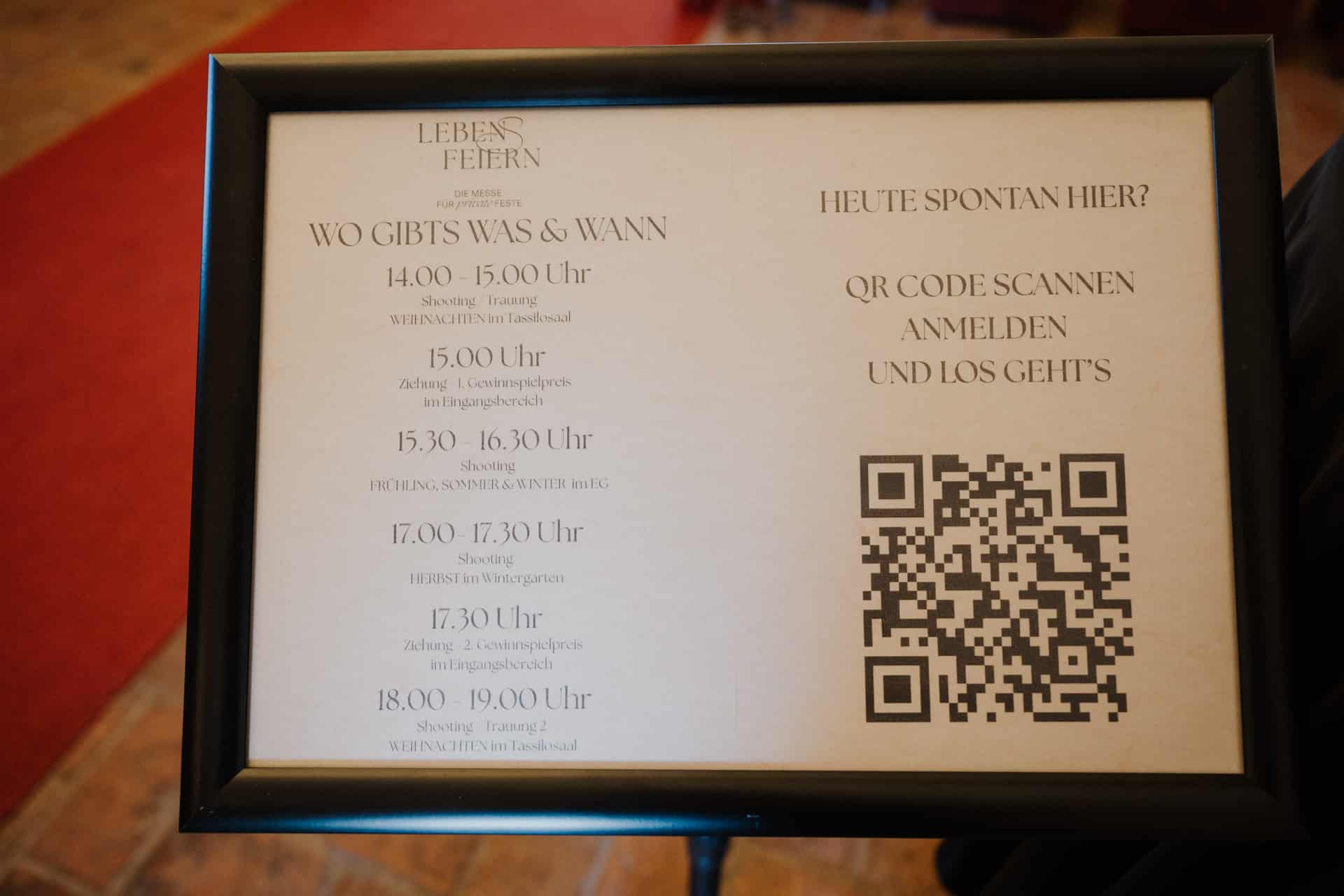 Ein gerahmtes Schild in deutscher Sprache zeigt einen Veranstaltungsplan mit Zeiten von 14:00 bis 19:00 Uhr, Details zu den Aktivitäten und einen großen QR-Code auf der rechten Seite für die Anmeldung unter der Überschrift "HEUTE SPONTAN HIER?".