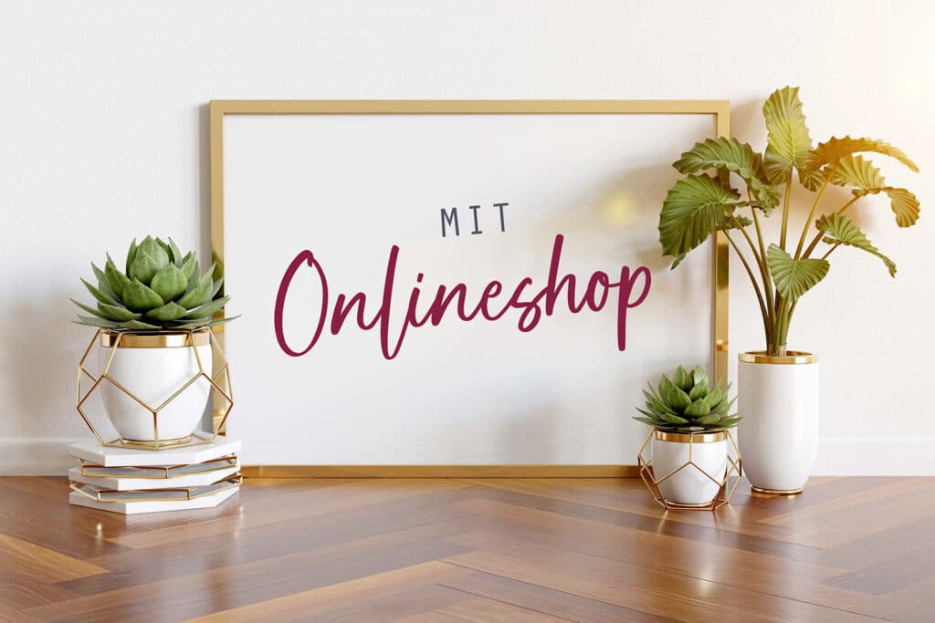 Ein gerahmtes Schild mit dem Text „MIT Onlineshop“ in stilvoller Schriftart lehnt an einer Wand, umgeben von zwei Sukkulenten und einer Blattpflanze, alle in geometrischen Töpfen auf einem Holzboden. Perfekt für alle, die ihre Traumhochzeit planen oder nach einzigartigen Heiratsutensilien suchen.