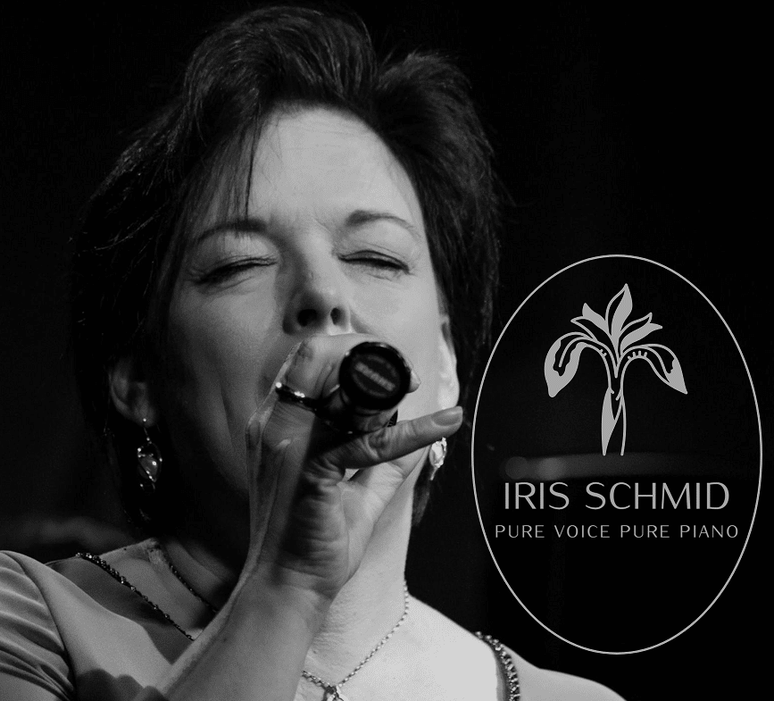 Ein Schwarzweißfoto zeigt eine Frau, die mit geschlossenen Augen in ein Mikrofon singt und so die Romantik einer Hochzeit heraufbeschwört. Neben ihr steht das Logo „Iris Schmid, Pure Voice Pure Piano“ mit einem stilisierten Pflanzendesign – eine perfekte Harmonie für Ihre Hochzeitsplanung.