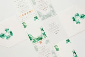 Flache Hochzeitseinladungskarten mit tropischen Blattmotiven, umgeben von passenden Umschlägen. Das Set zeichnet sich durch elegante Typografie und ein natürliches Thema aus, das Grün und Einfachheit betont – perfekt für diejenigen, die gerade mitten in der Hochzeitsplanung stecken.