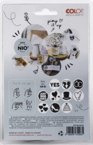 Ein Verpackungsdesign eines Stempelsets zeigt verschiedene Symbole und Sätze wie „JA“ und „JUST MARRIED“, perfekt für die Hochzeitsplanung. Enthält handgezeichnete Anweisungen und ein Foto eines dekorierten Tisches. Die Marke „Colop Arts & Crafts“ ist oben rechts sichtbar.