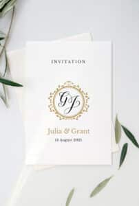 Eine Hochzeitseinladung mit elegantem Design zeigt ein Monogramm „GJ“, das von einem goldenen Blumenmotiv umgeben ist. Als Highlight der Hochzeit von Julia & Grant am 13. August 2021 verleihen Olivenzweige der Einladung Charme, perfekt für eine sorgfältige Hochzeitsplanung.