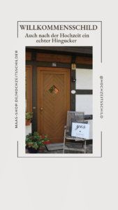 Eine rustikale Holztür mit einem Fenster im Rautenmuster schmückt das Fachwerkhaus. In der Nähe steht ein Stuhl mit einem weißen Schild mit der Aufschrift „Ja“, perfekt für jede Hochzeit. Topfpflanzen verleihen dem Eingang unter dem einladenden „WILLKOMMENSSCHILD“ Charme.