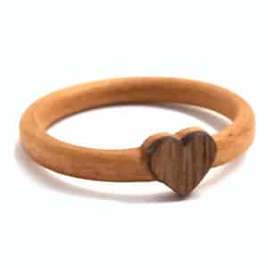 Ein einfacher Holzring mit einem kleinen herzförmigen Design in der Mitte, perfekt für alle, die ihre Hochzeit planen. Der Ring hat eine glatte, natürliche Holzoberfläche.