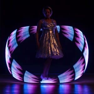 Eine Person in einem glänzenden Kleid steht in einem dunklen Raum, der an eine Hochzeitsfeier erinnert, umgeben von wirbelnden Neonlichtern in Pink und Blau, die ein kreisförmiges Muster um sie herum bilden.