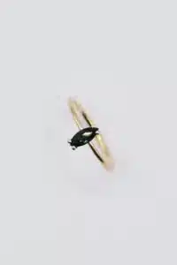 Ein goldener Ring mit einem dunkelgrünen Edelstein im Marquiseschliff in einem schlichten Band, perfekt für alle, die ihre Traumhochzeit planen. Vor einem schlichten weißen Hintergrund spiegelt er Eleganz und Schlichtheit wider und ist damit die ideale Wahl für Paare, die heiraten möchten.