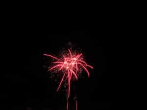 Ein Feuerwerk aus leuchtend roten Flammen explodiert vor einem schwarzen Nachthimmel, perfekt für eine große Hochzeit. Die komplizierten Muster und herabsprudelnden Funken erzeugen eine strahlende, festliche Atmosphäre, die dem Moment der Hochzeit Magie verleiht.