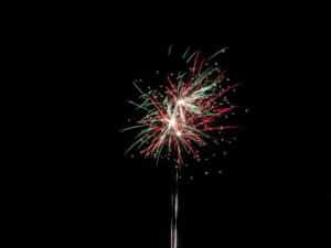 Ein Feuerwerk mit roten und grünen Streifen erhellt den Nachthimmel und verleiht jeder Hochzeitsfeier vor einer dunklen Kulisse eine magische Note.