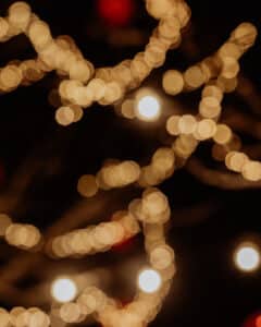 Unscharfes Bild, das Bokeh-Lichter in warmen Tönen vor einem dunklen Hintergrund zeigt und eine festliche und verträumte Atmosphäre schafft.