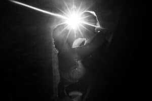 Ein Paar umarmt sich eng in der Silhouette, wobei ein helles Licht hinter ihnen einen dramatischen Starburst-Effekt erzeugt und die romantische Stimmung unterstreicht.